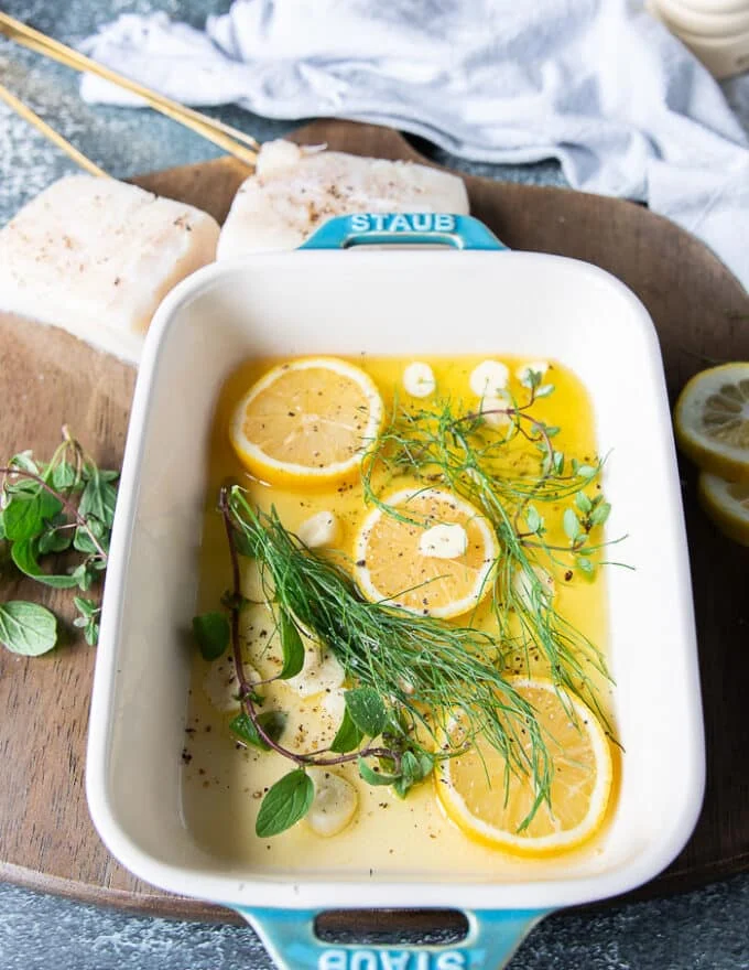 The bottom of the oven safe dish is then layered with sliced garlic, lemon slices and fresh herbs before the halibut fish is added.