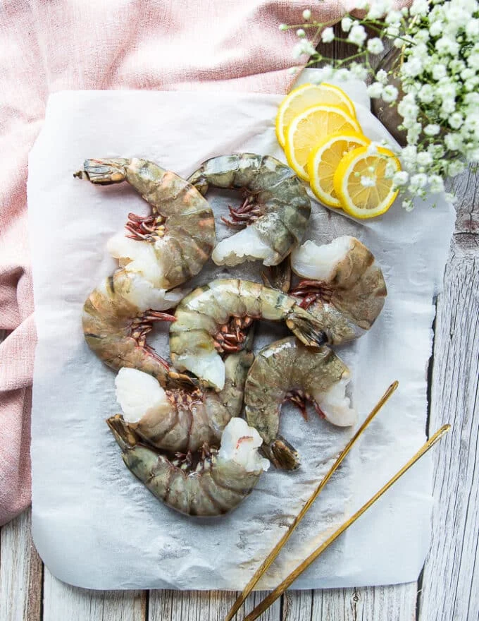 large shrimp that's being used for shrimp scampi on parchment paper