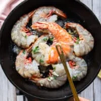 A hand showing one of the shrimp beginning to turn pink and ready to flip