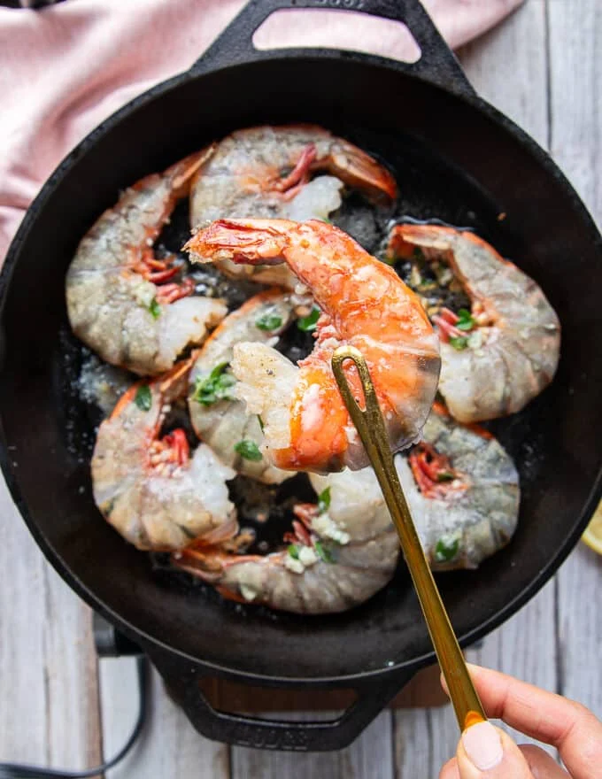 A hand showing one of the shrimp beginning to turn pink and ready to flip