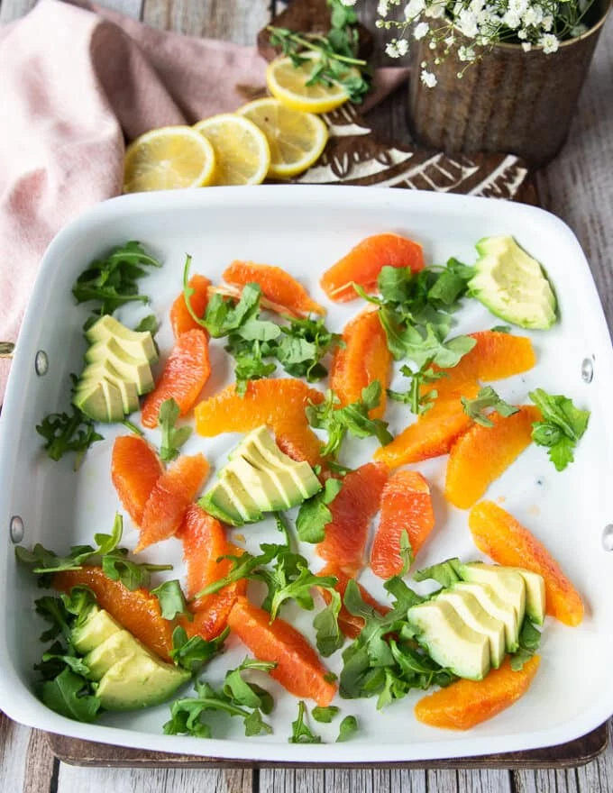 orange avocado salad base for the grilled mahi mahi on a plate with avocado slices , orange segments and arugula