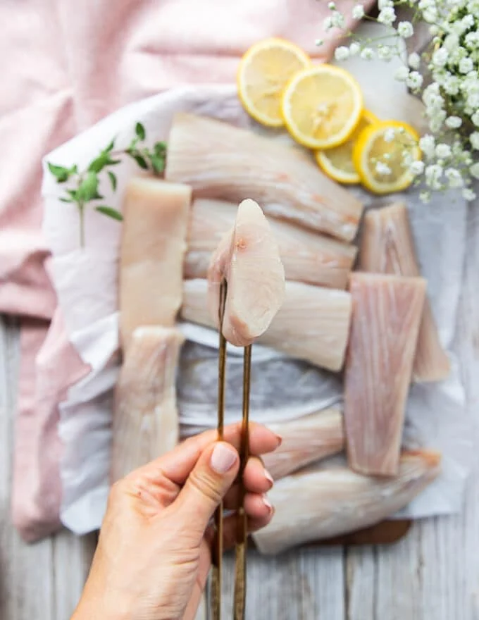 close up of a hand holding one piece of mahi mahi fillets showing the firm texture of the fillet and how it is ideal for grilling