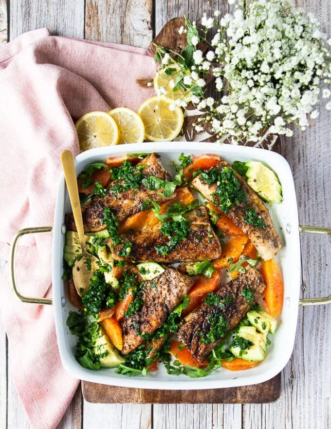 A plate of grilled Mahi mahi over orange segments and avocados, drizzled with herbs, olive oil and orange juice.