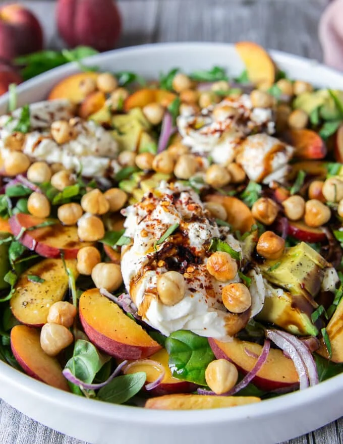 close up of the final dressed peach burrata salad showing the peaches and creamy burrata with a balsamic glaze