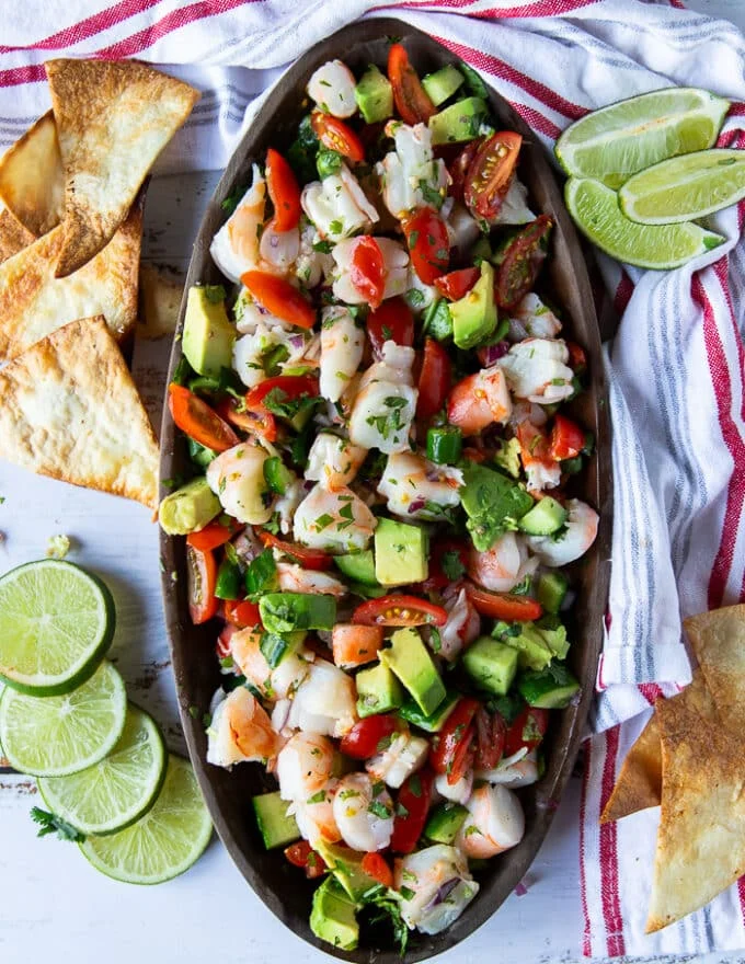 Final plate of shrimp ceviche with all ingredients ready and some chips around it for serving