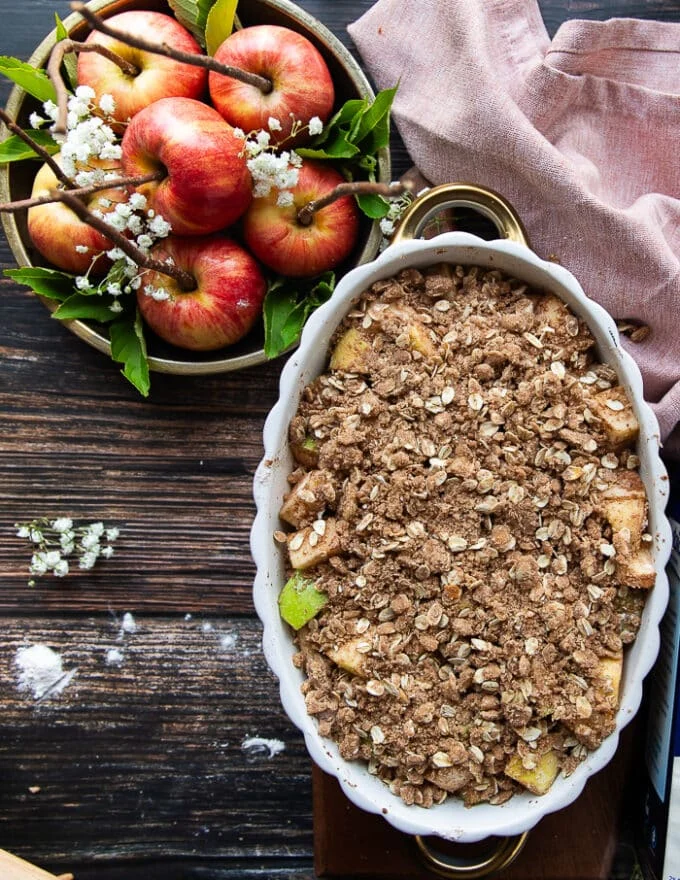 The oat crisp topping is added all over the apples in the baking dish and now the apple crisp is ready to bake