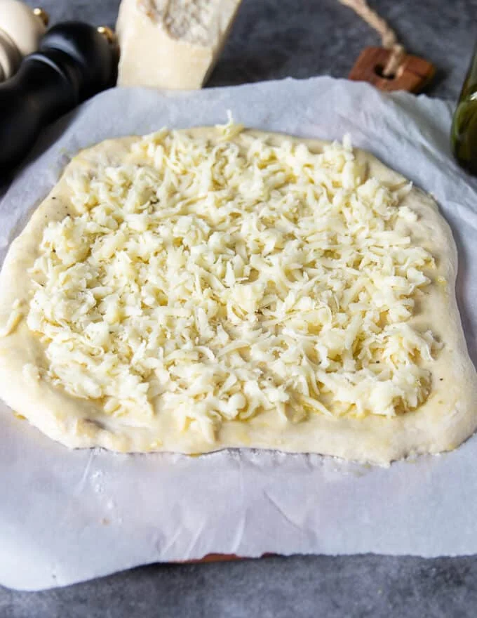 A thin layer of mozzarella cheese is added over the dough to make the pizza extra cheesy--optional