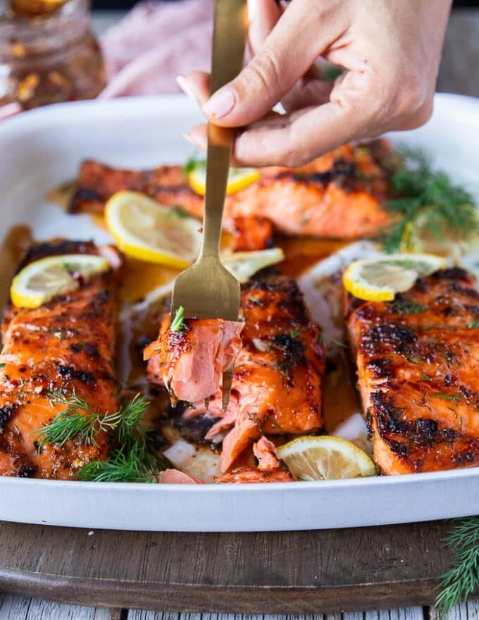 A hand holding a fork and showing a bite of honey glazed salmon recipe