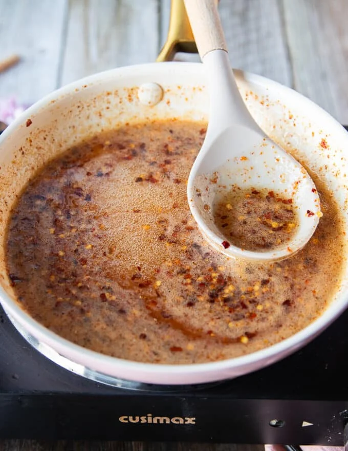 Honey and chili flakes in the sauce pan simmering on the edges and not boiling