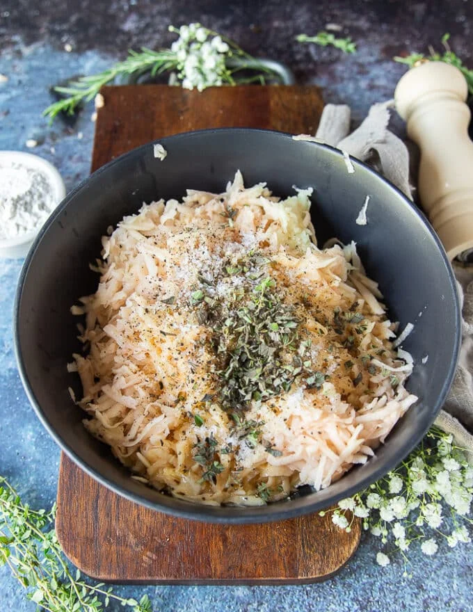 The remanning ingredients are added to the potato bowl such as flour, herbs and seasoning