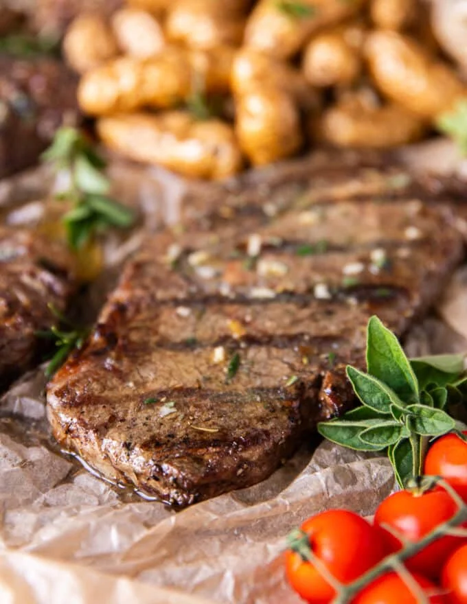 Close up of a ribeye steak cooked perfectly on the grill with grill mark and some melted butter on top