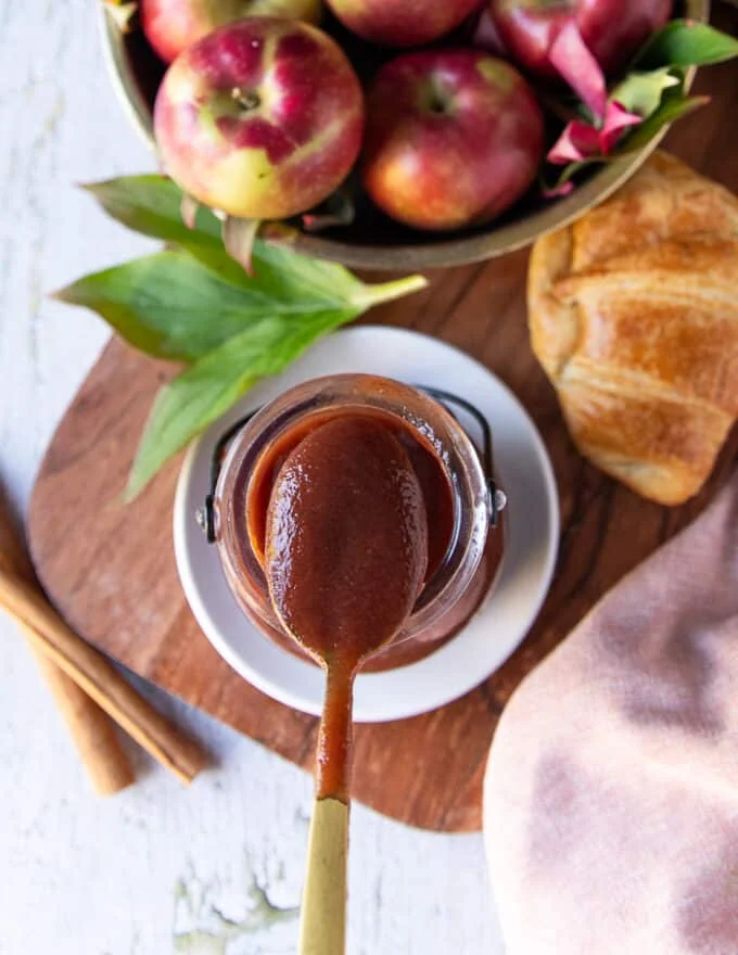 A spoon scooping apple butter from the jar showing close up of the thick and smooth texture