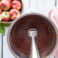 An immersion blender pureeing the apple butter until smooth
