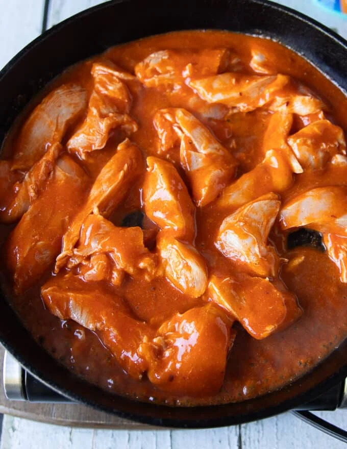 The chicken and sauces are all added into a heavy cast iron skillet with sauce and everything