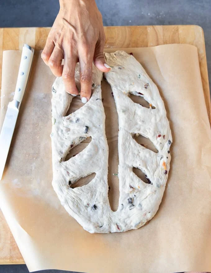Tip: A hand opening the slits gently made ont he dough to make sure they remain slits and not seal as the dough rises again.