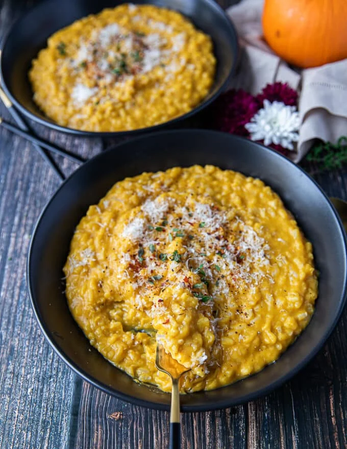 A plate of pumpkin risotto with a fork swirling it to show the texture of the risotto