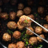 The air fryer meatballs ready and cooked, and a tong holding one meatballs close enough to show the details of the cooked air fryer meatballs