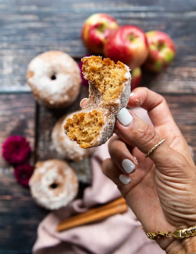 a hand holding one bit off donut to show how fluffy and soft the donut recipe is