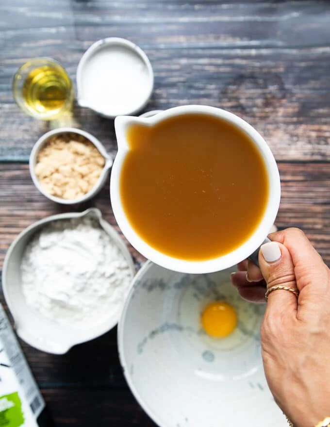 A hand holding the apple cider in a large cup ready to boil it down