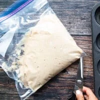 A hand using a scissors to snip off the corner or the ziploc bag