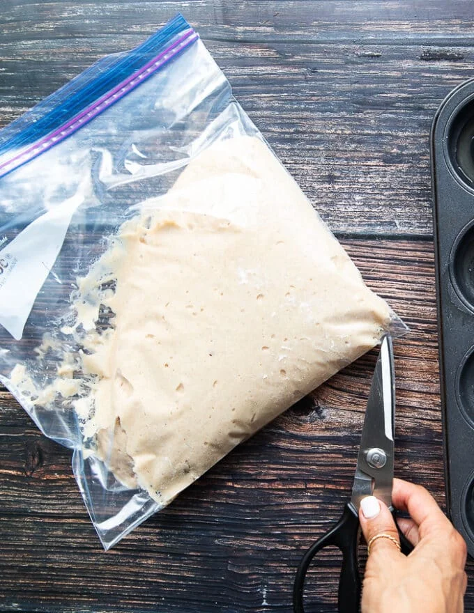 A hand using a scissors to snip off the corner or the ziploc bag
