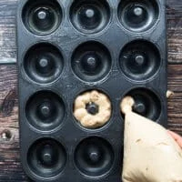 The apple cider donut being pumped into the muffin pan