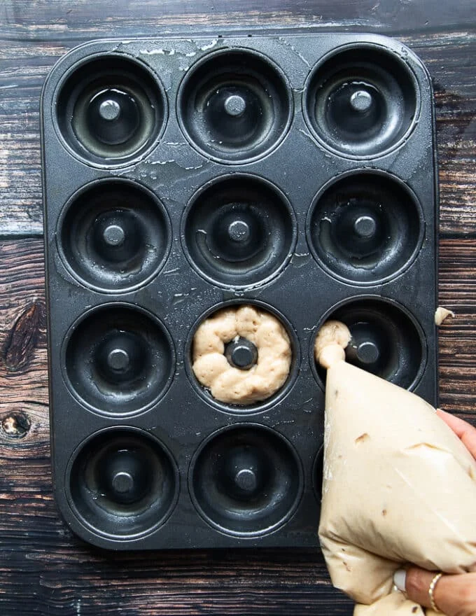 The apple cider donut being pumped into the muffin pan
