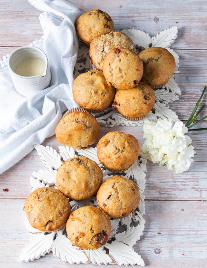 A spread of 12 banana bread muffins out of the oven just placed on a table waiting to cool
