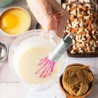 A hand holding some cream cheese glaze ready ahead of time.