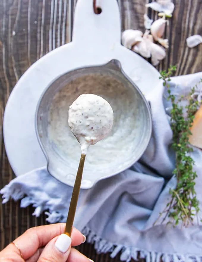 The garlic parmesan sauce mixed in the bowl and a spoon showing off the final texture