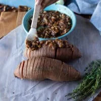 A hand repeating the same with the sweet mixture, adding the pecan cinnamon sugar mixture between the slices of sweet potatoes