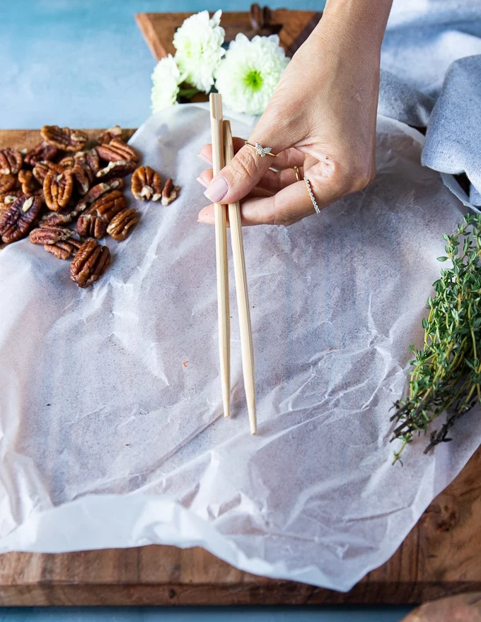 A hand holding two chopsticks over the cutting board