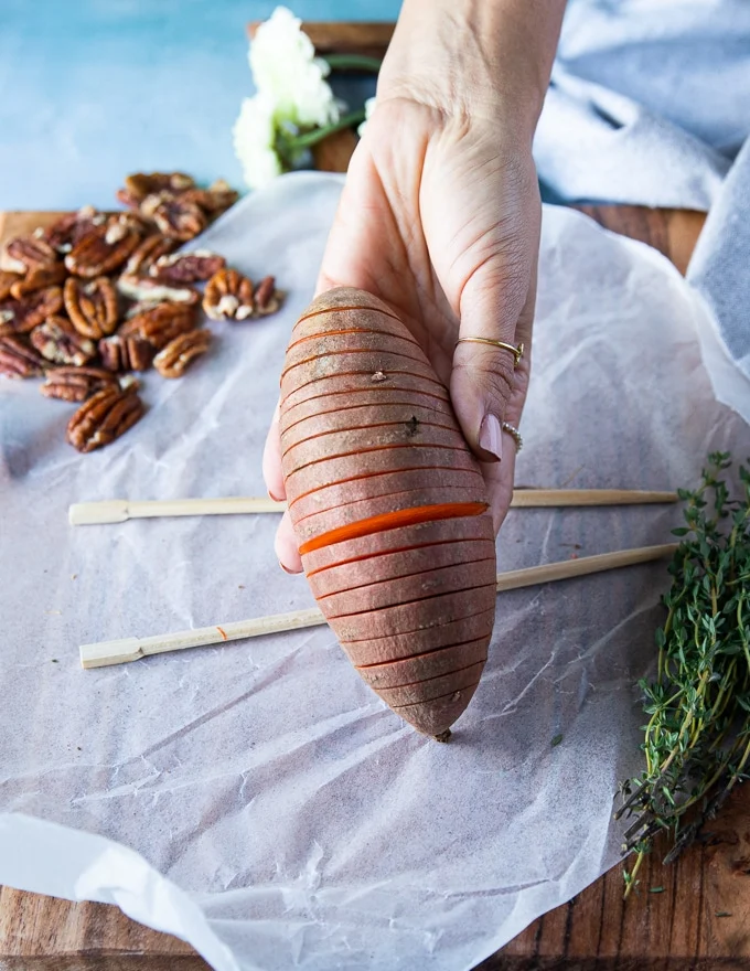 A hand showing the finished sliced hasselback sweet potato and how it should look