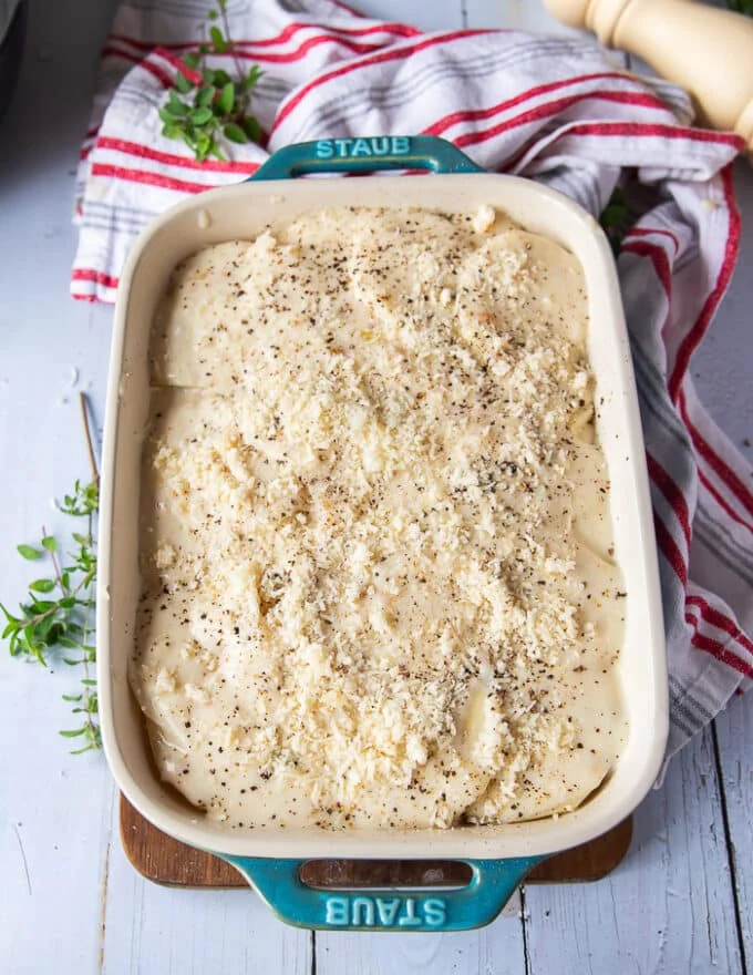 The final layer of cream sauce and cheese is added over the potatoes to complete the scallop potatoes dish