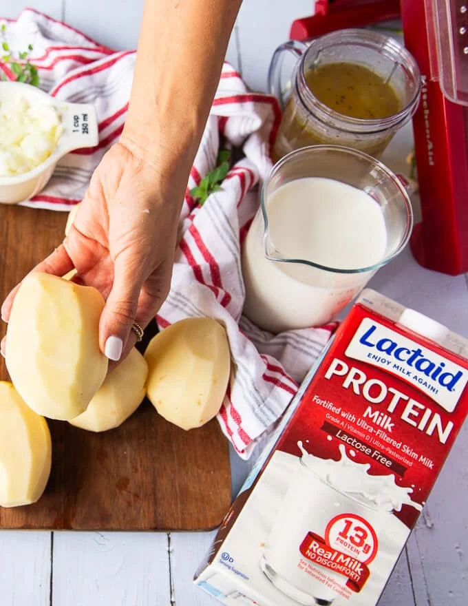 A hand holding peeled yellow potatoes