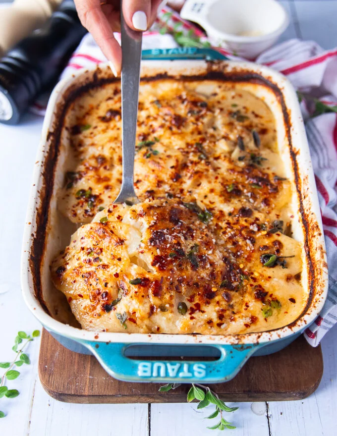 A spoon scooping out a serving os scalloped potatoes showing the texture of cooked potatoes