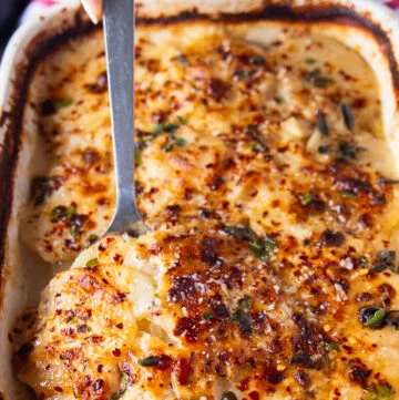 close up of scalloped potatoes portion removed with a spoon showing the texture of the cooked soft potatoes and a cheesy top golden crust
