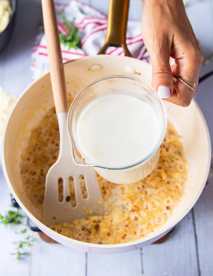 A hand pouring in the milk into the pan