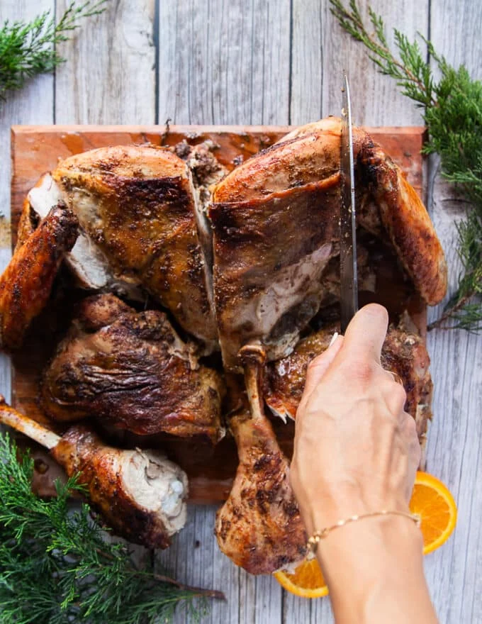 A hand separating the wings from the breast to complete carving out the turkey recipe