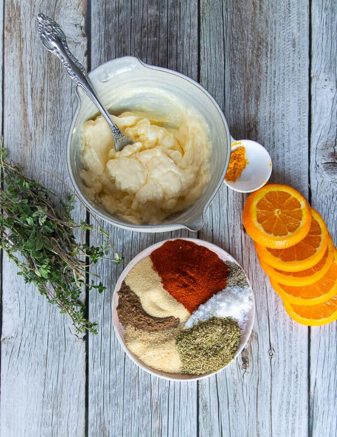 Ingredients for the turkey butter including a bowl of soft butter, some orange zest and a plate full of spices like salt, pepper, paprika, oregano, onions powder, garlic powder