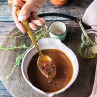 A bowl with the finished salad dressing and a hand holding a spoon to show the consistency of the salad dressing
