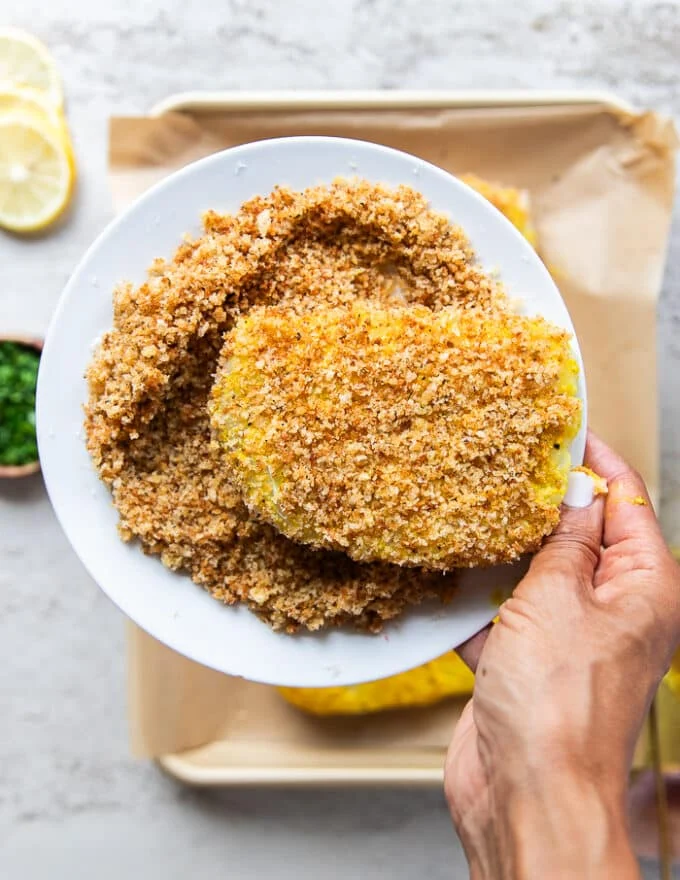 a hand holding the panko coated fish tops to show the coating