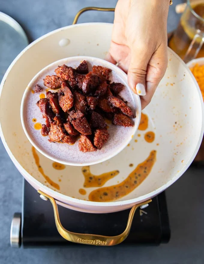 The crumbled bacon or sausage is removed on to a plate