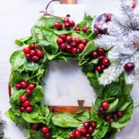 optional way of serving for the holidays-- a wreath made by fresh baby spinach leaves in a round shape, and then some fresh cranberries dotted aver the wreath to make it look super festive and placed over a round white marble