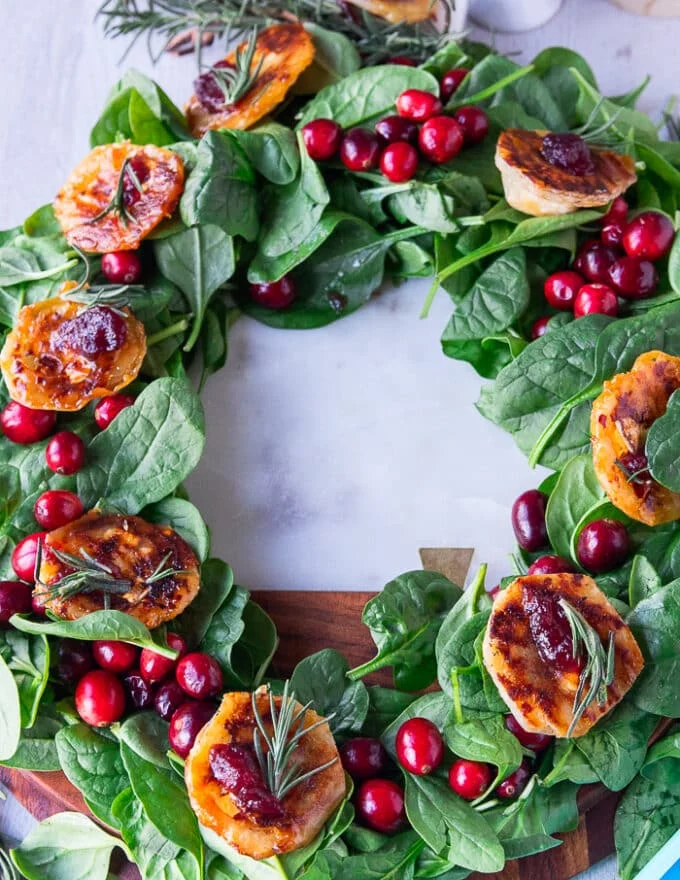 Cranberry brie bites right out of the oven and placed oven the spinach wreath and topped with cranberry sauce and fresh rosemary