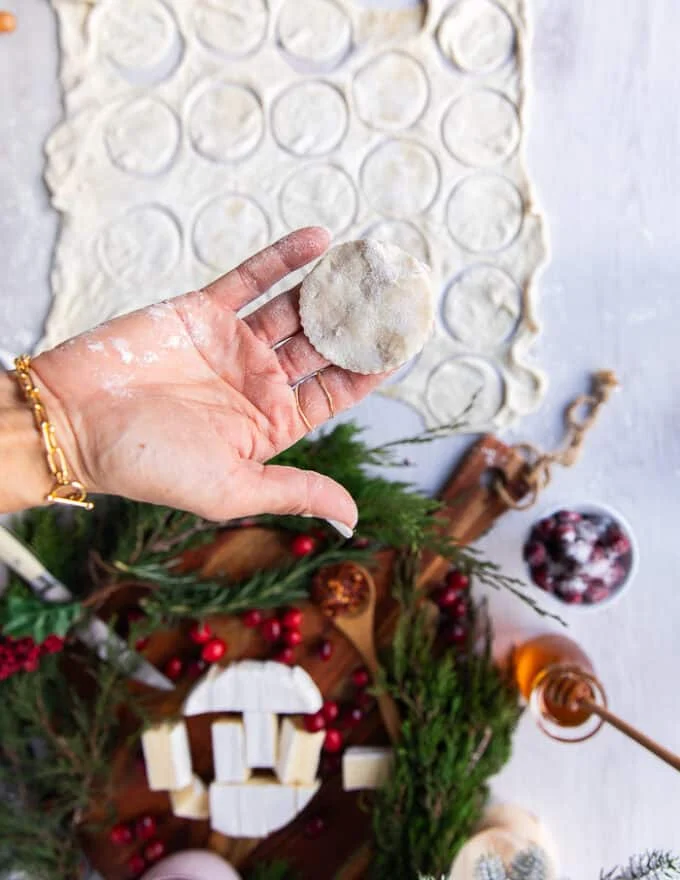 A hand holding a cut up round of puff pastry