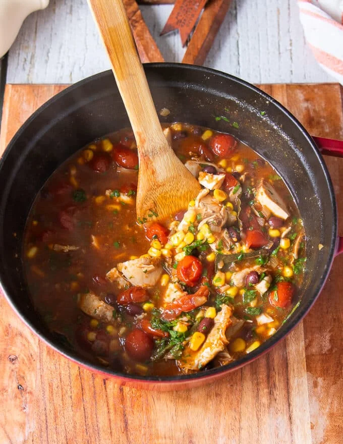 the chicken tortilla soup recipe is ready in the post and a wooden spoon is scooping some soup to show off how it looks