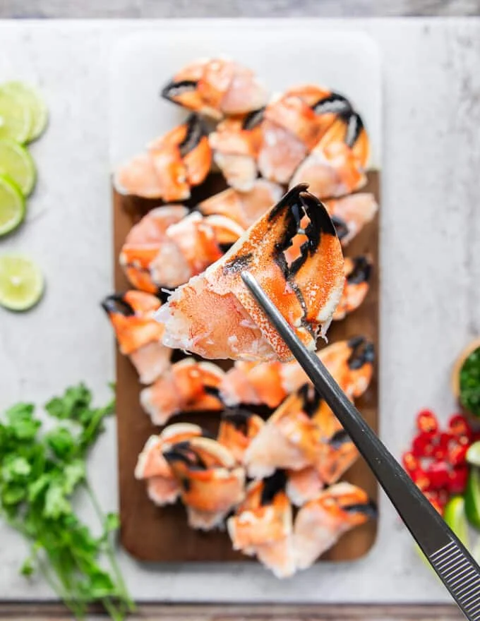 A hand holding a piece of defrosted jonah crab claw showing how it should be before cooking
