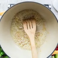 Butter heating up in a large pot with garlic sautéing over medium heat
