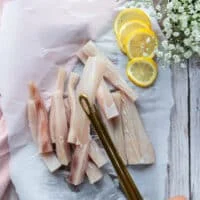 A hand holding cut up mahi mahi fish into fish fingers shape